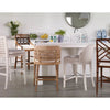 Five different counter stools are arranged around a white kitchen island with decorative items, plants, and a round mirror on the wall in the background.