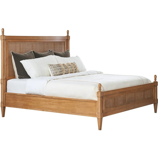 A wooden bed with a high headboard and low footboard, dressed with white bedding, decorative pillows, and dark accent pillows.