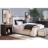 Luxury upholstered bed with a curved frame, dark wood demilune nightstand, matching dresser, table lamps, and modern bedroom decor in neutral tones.