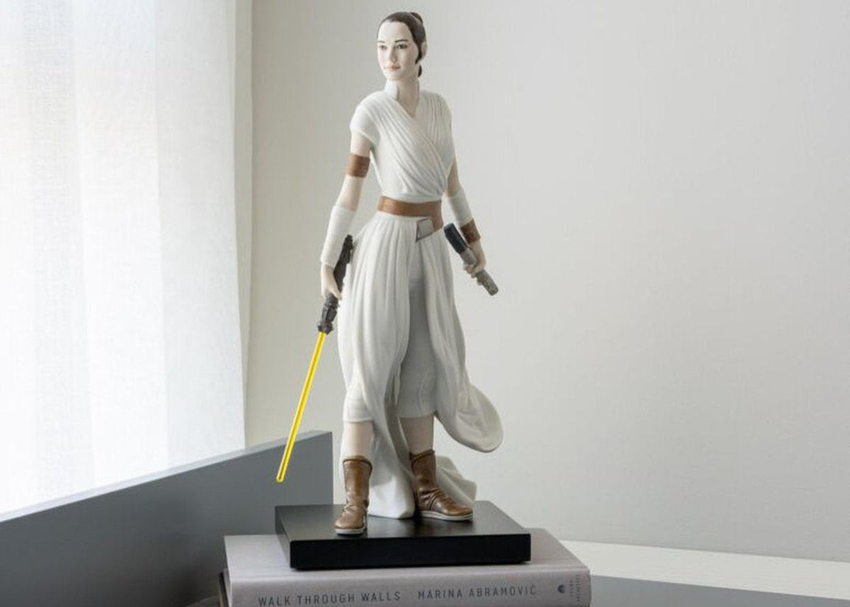 Star Wars figurine of a female character on a book with a notebook and pen on a table, Lladro branding visible.