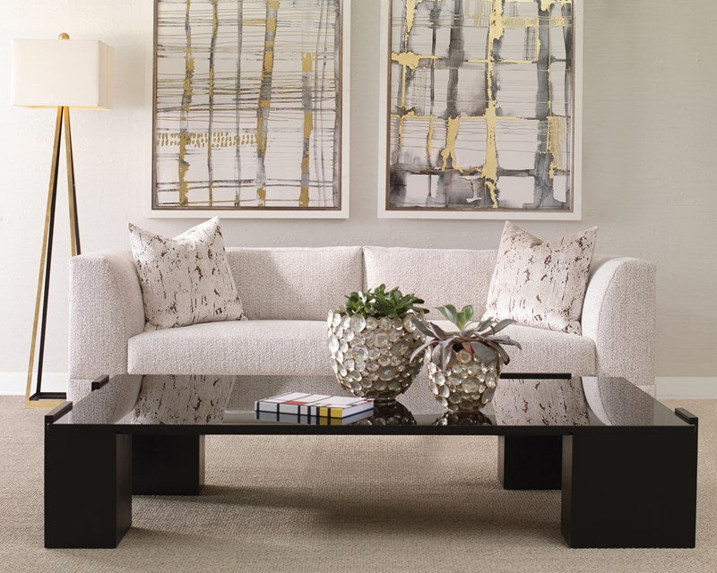 Modern living room with a gray sofa, black coffee table, and abstract art on the wall.