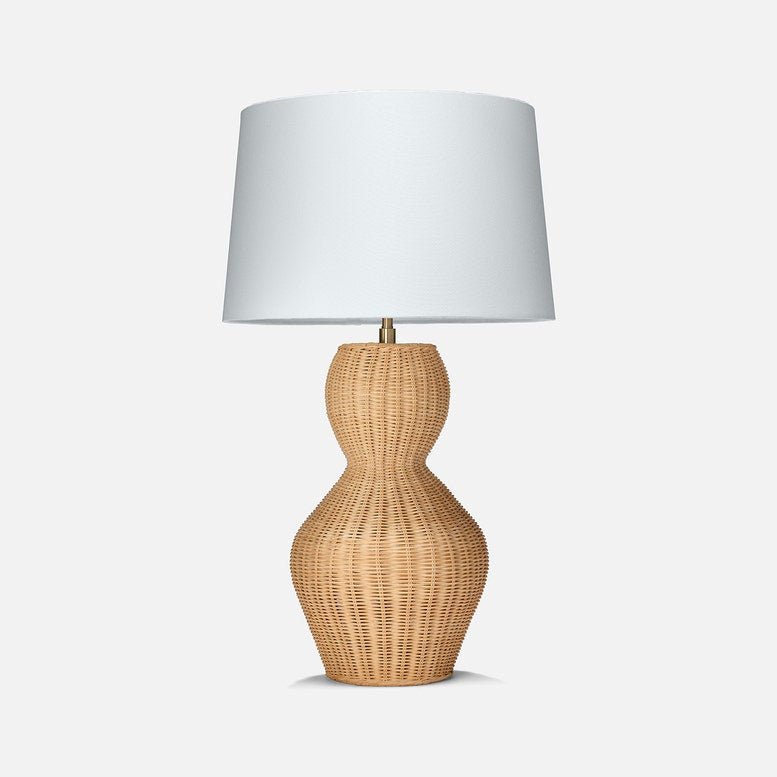A stylish Lucena table lamp featuring a woven rattan base with an hourglass shape and a simple white lampshade on top.