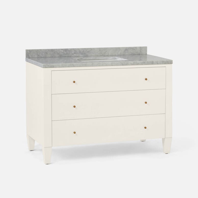 Elegant cream vanity with three drawers and a light gray marble countertop featuring a cutout for a sink.