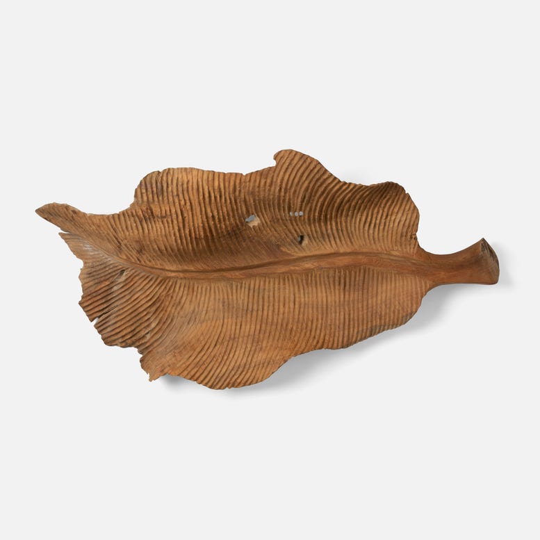 A carved wooden leaf-shaped tray with detailed grooves and a natural finish, showcasing organic beauty and craftsmanship.